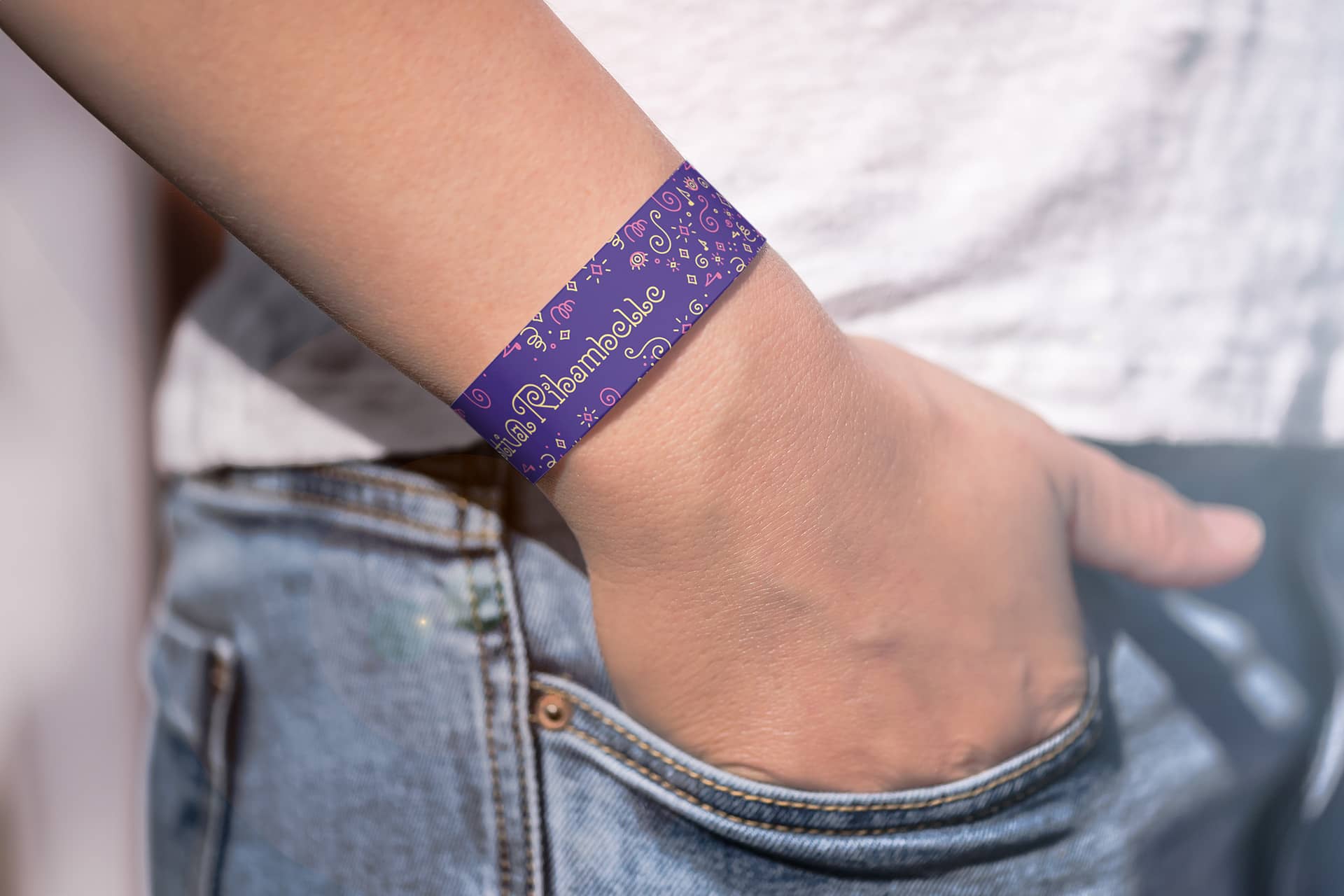 Un poignet portant le bracelet en papier du Festival Ribambelle